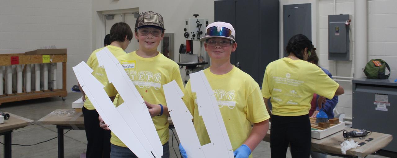 Students hold up their fuselages they made from STEPS 2026